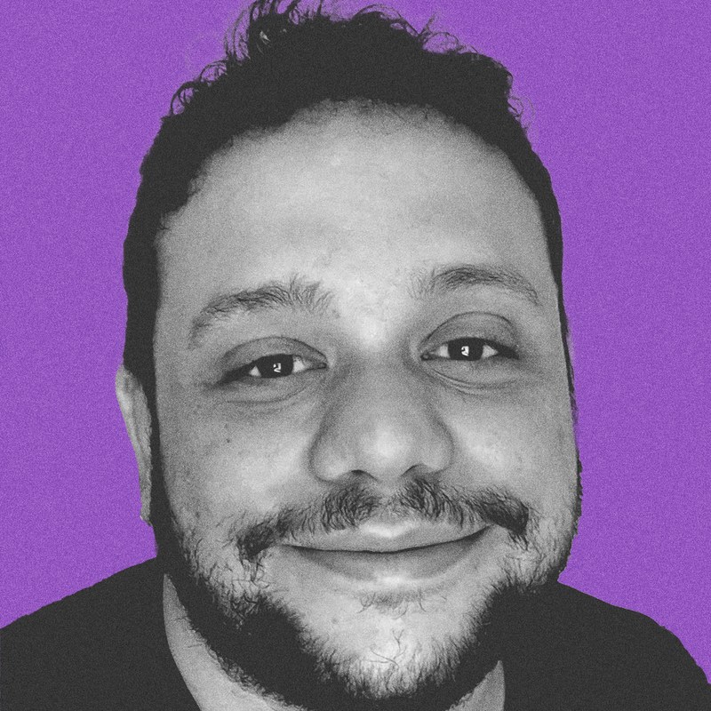 Retrato do Jorge Curti em preto e branco sobre fundo roxo.